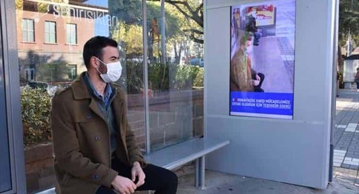Duraklardaki ekran maske takmayanların yüzünü koronavirüsüne çeviriyor